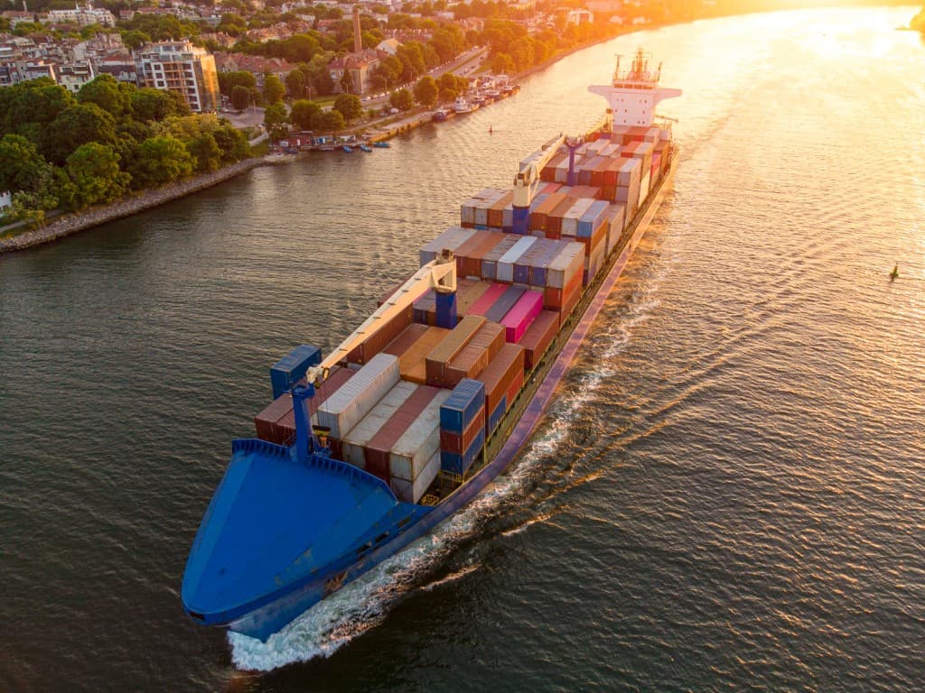 Container ship carrying cargo on a river at sunset